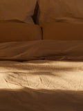 beige bedding with a rumpled comforter and pillows.