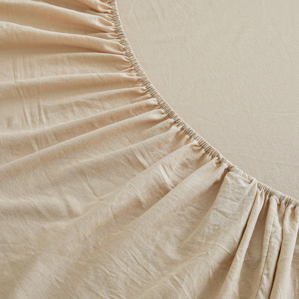 Close-up of beige fitted sheet with a slight texture on a neutral background